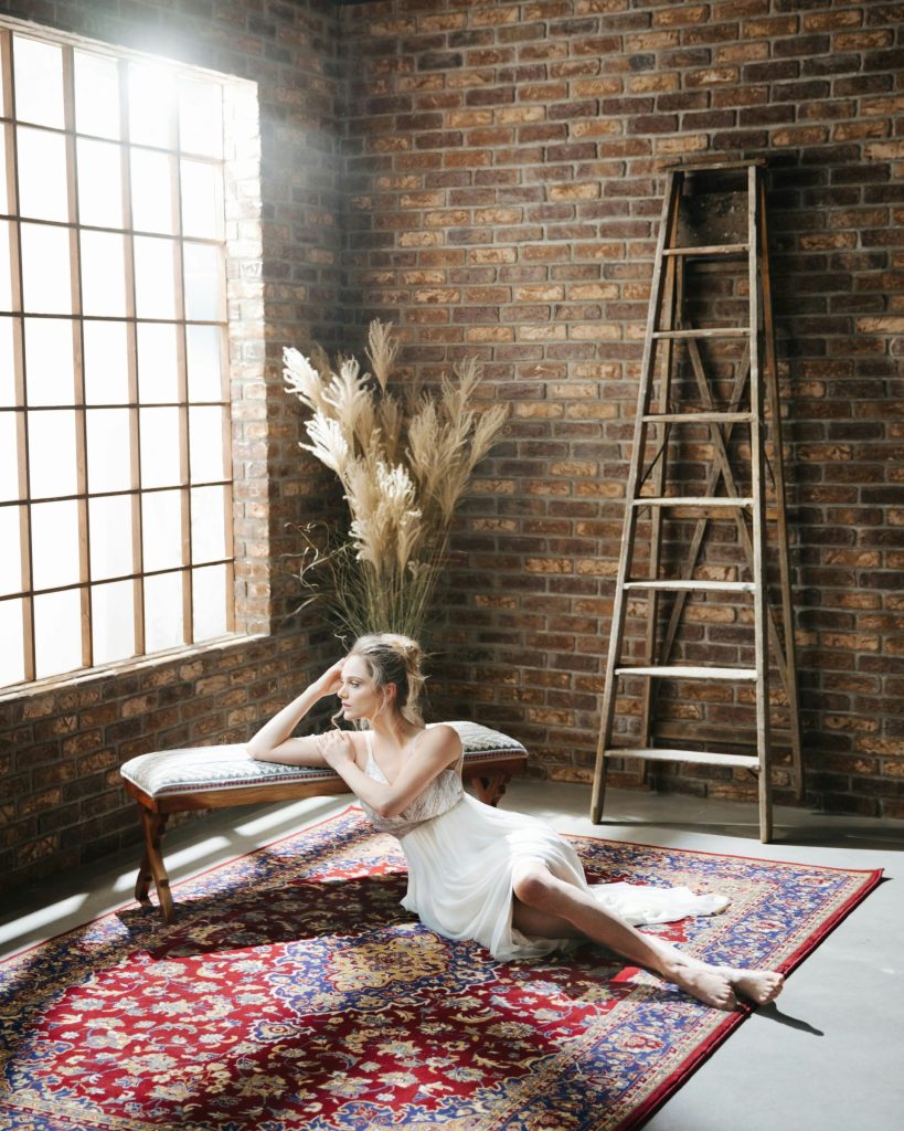 a woman in a white dress sitting on a rug