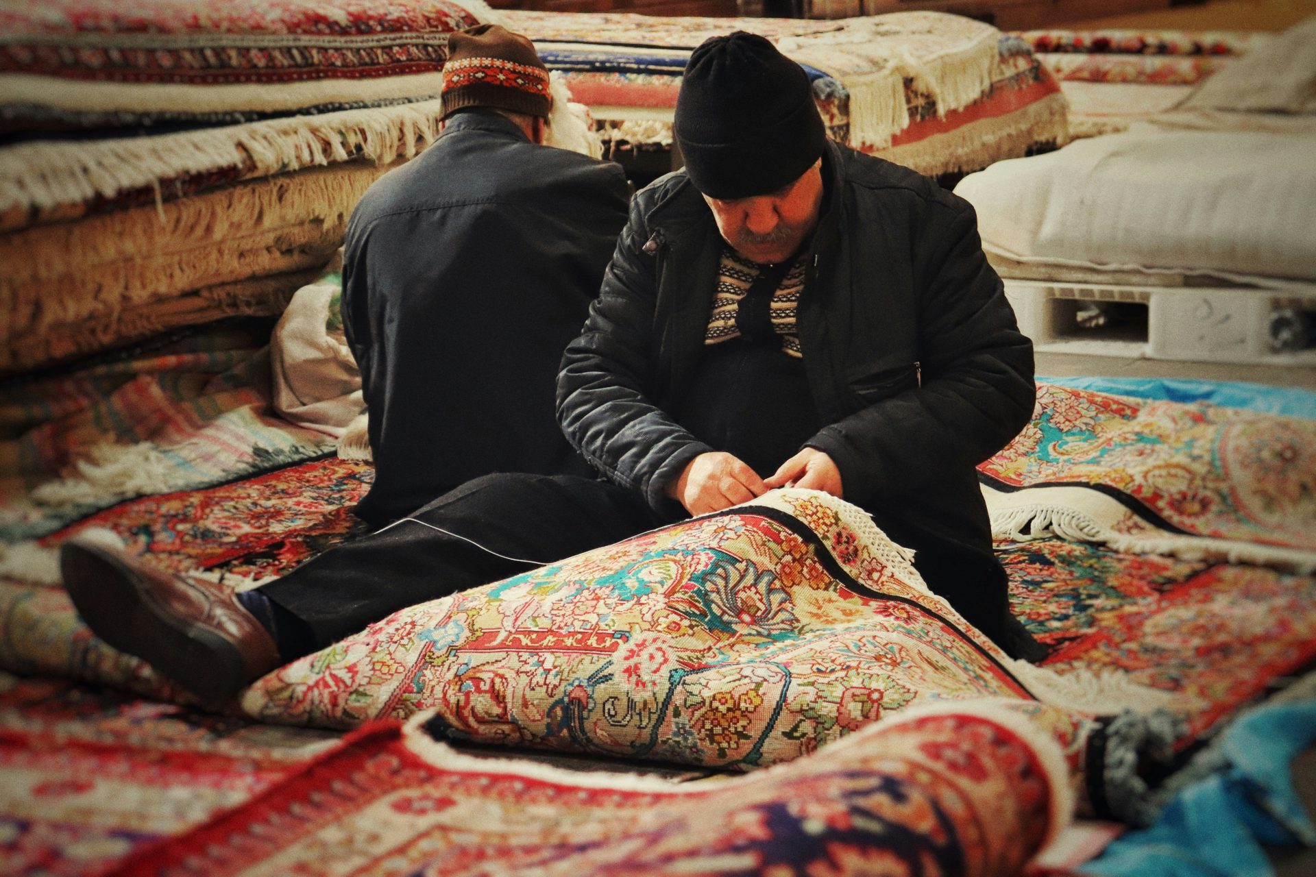 A man sitting on the ground next to a pile of blankets