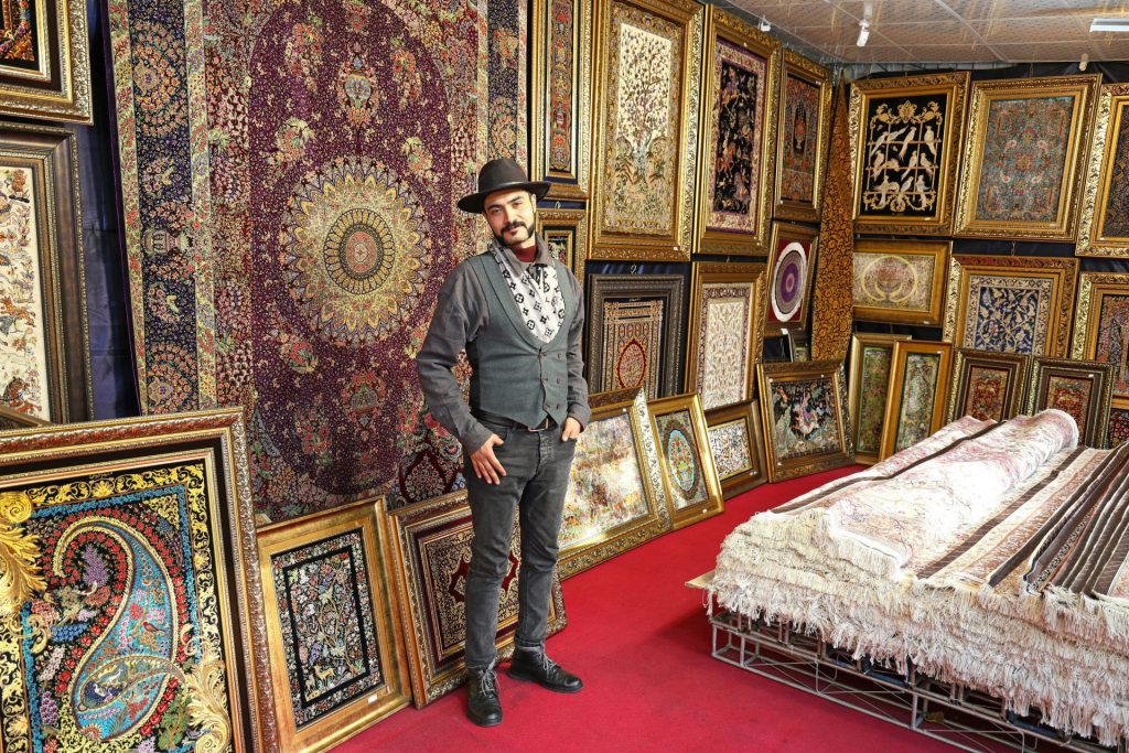 Man standing in a shop filled with carpets